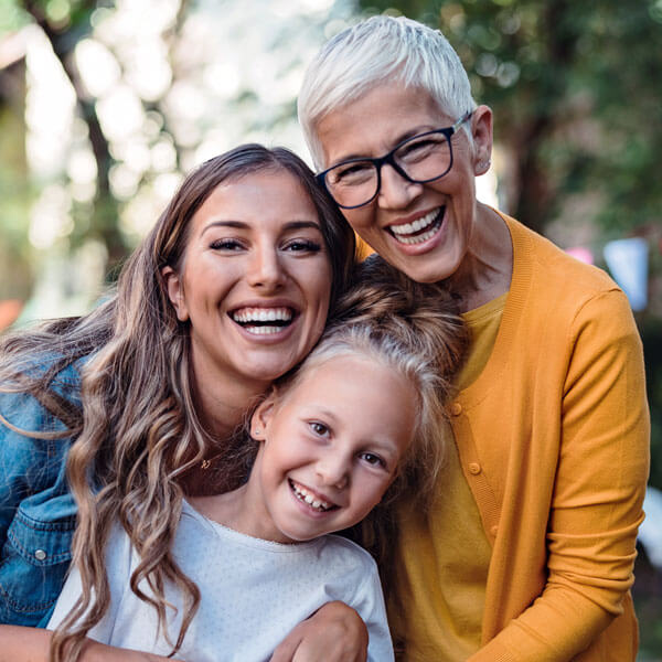 mother and daughter smiling with grandmother outdoors